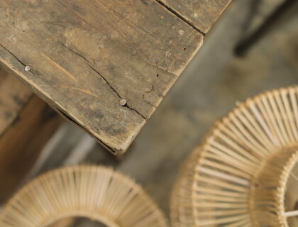 Detail van een houten tafel en een stoel met gevlochten zitting